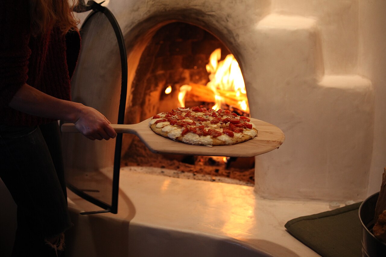 Il pizzaiolo inforna una pizza nel forno