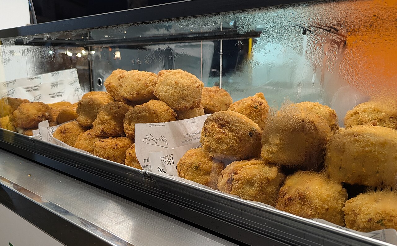 Frittatine e arancini dorati nella vetrina della friggitoria